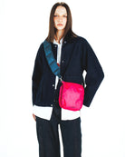 Model showcasing the Cassette Sacoche Medium Moss Tech Sateen Bag in pink, styled with a denim jacket.