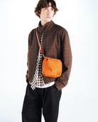 Model wearing the Cassette Sacoche Medium Moss Tech Sateen Bag in a stylish outfit.