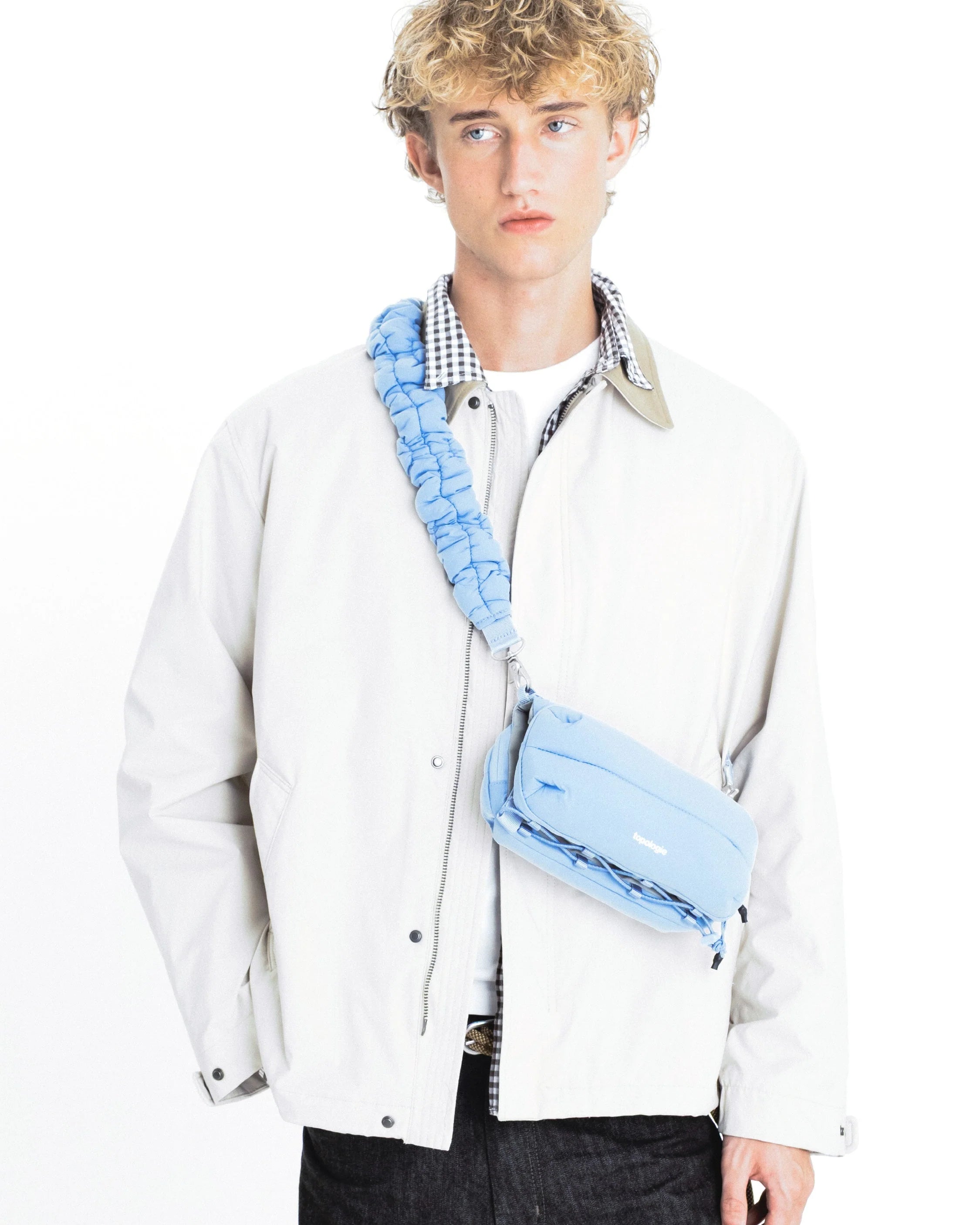 Model wearing a light jacket with a Cloud Strap Chambray Silky Peach bag, showcasing adjustable strap and stylish design.