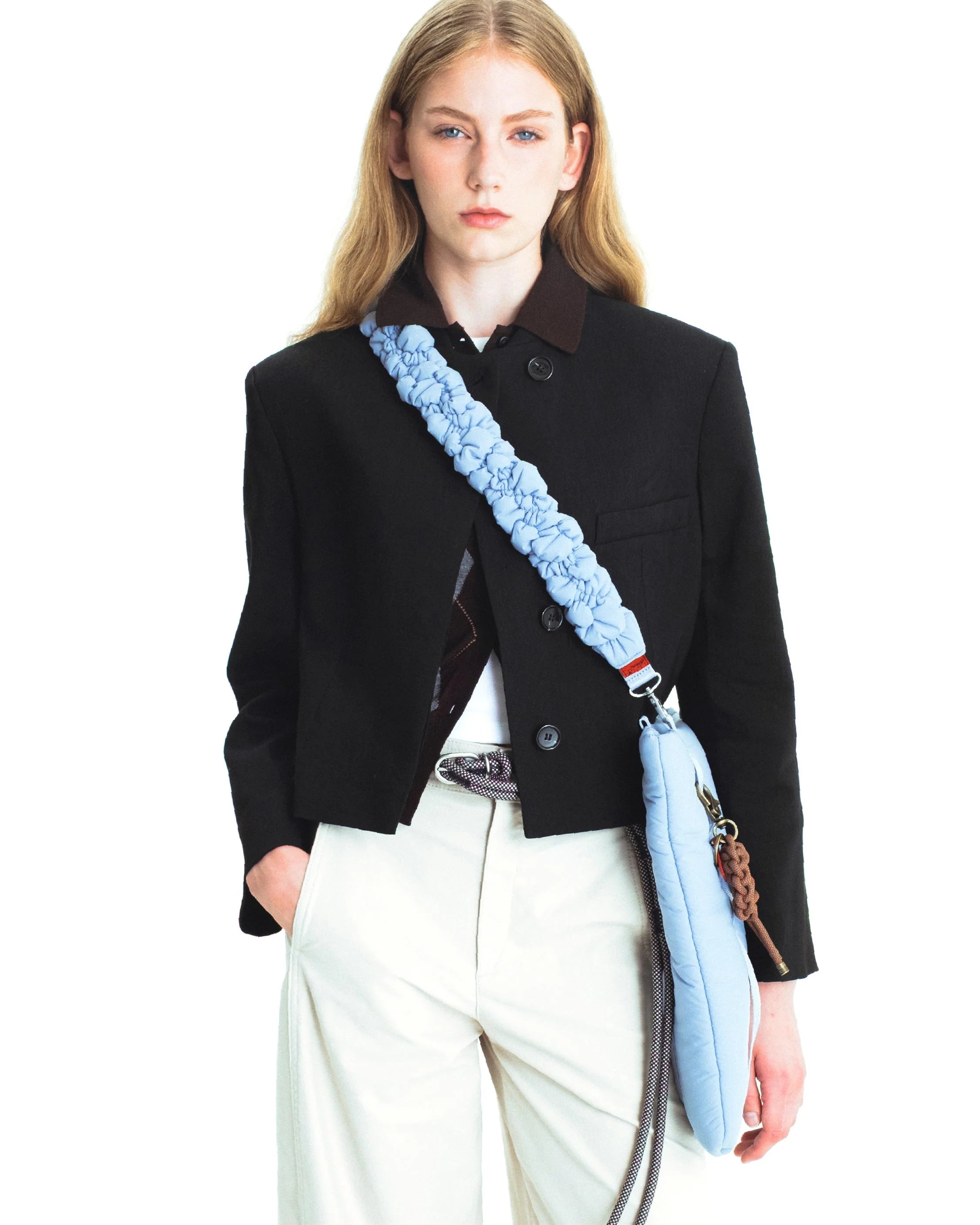 Model wearing a black jacket with a Cloud Strap Moss Silky Peach shoulder strap, showcasing style and comfort.