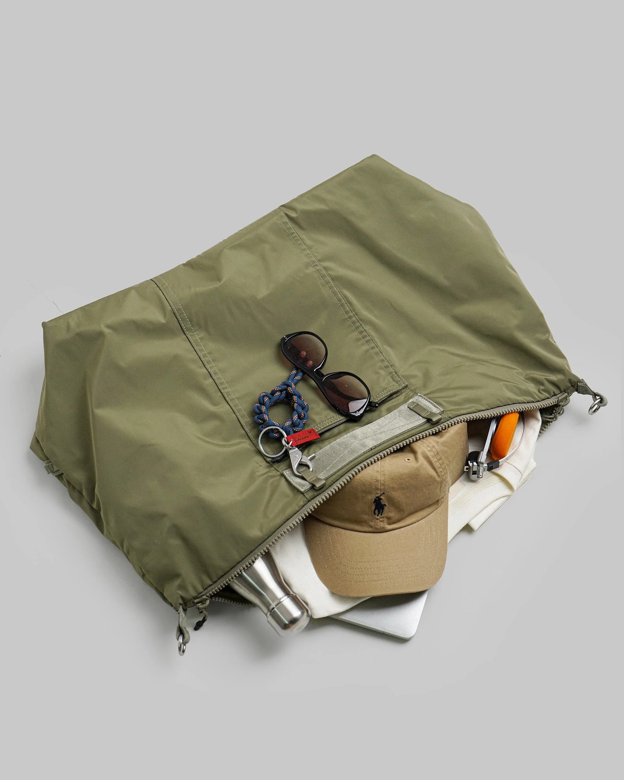Explorer Tote Weekender Moss Tech Sateen Shoulder Bag packed with accessories, sunglasses, cap, and clothing.