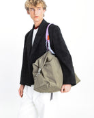 Explorer Tote Weekender Moss Tech Sateen Shoulder Bag styled on a model wearing a black blazer.