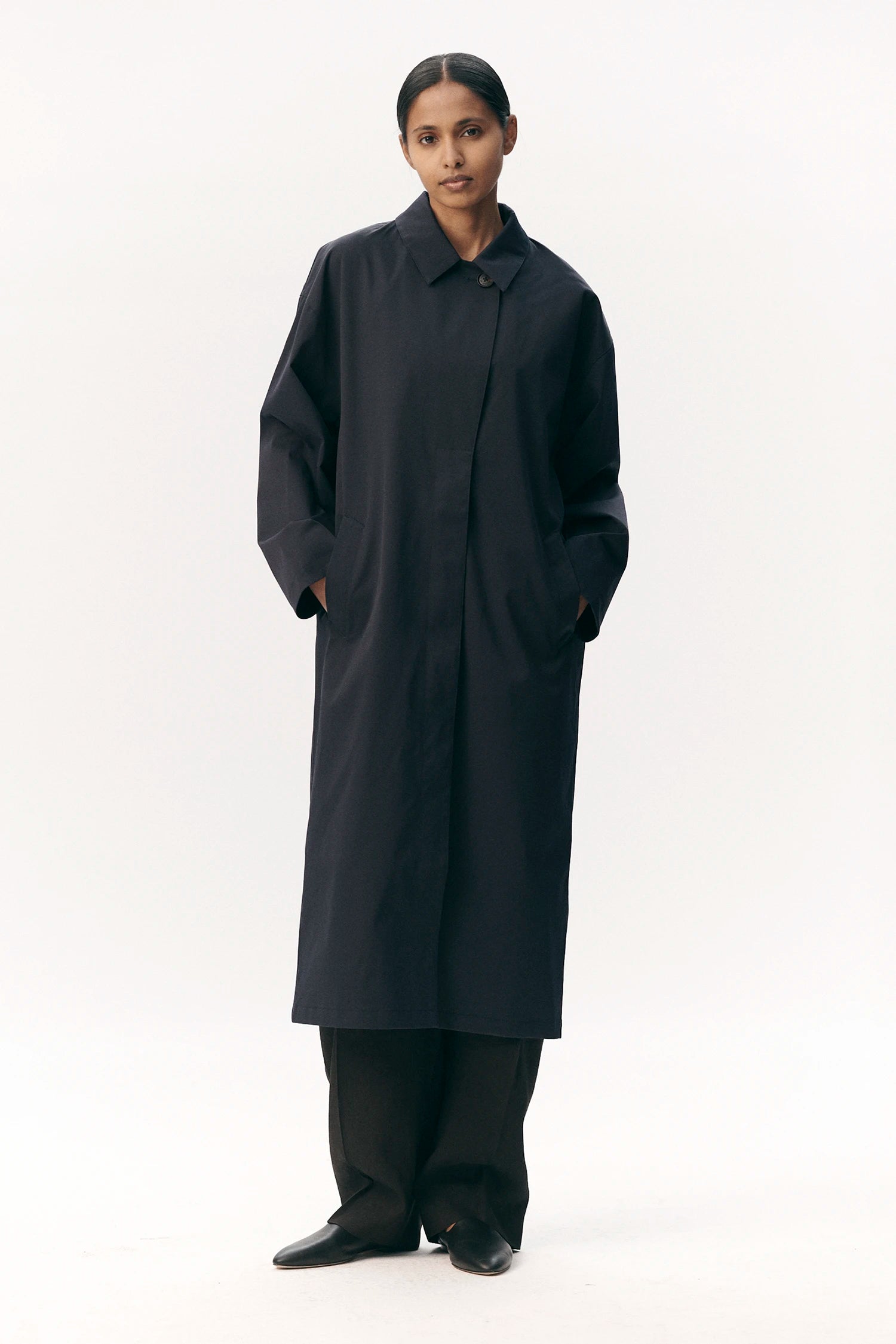 Model wearing Janice B Navy Coat, a lightweight waterproof jacket with a hidden hood and horn buttons.
