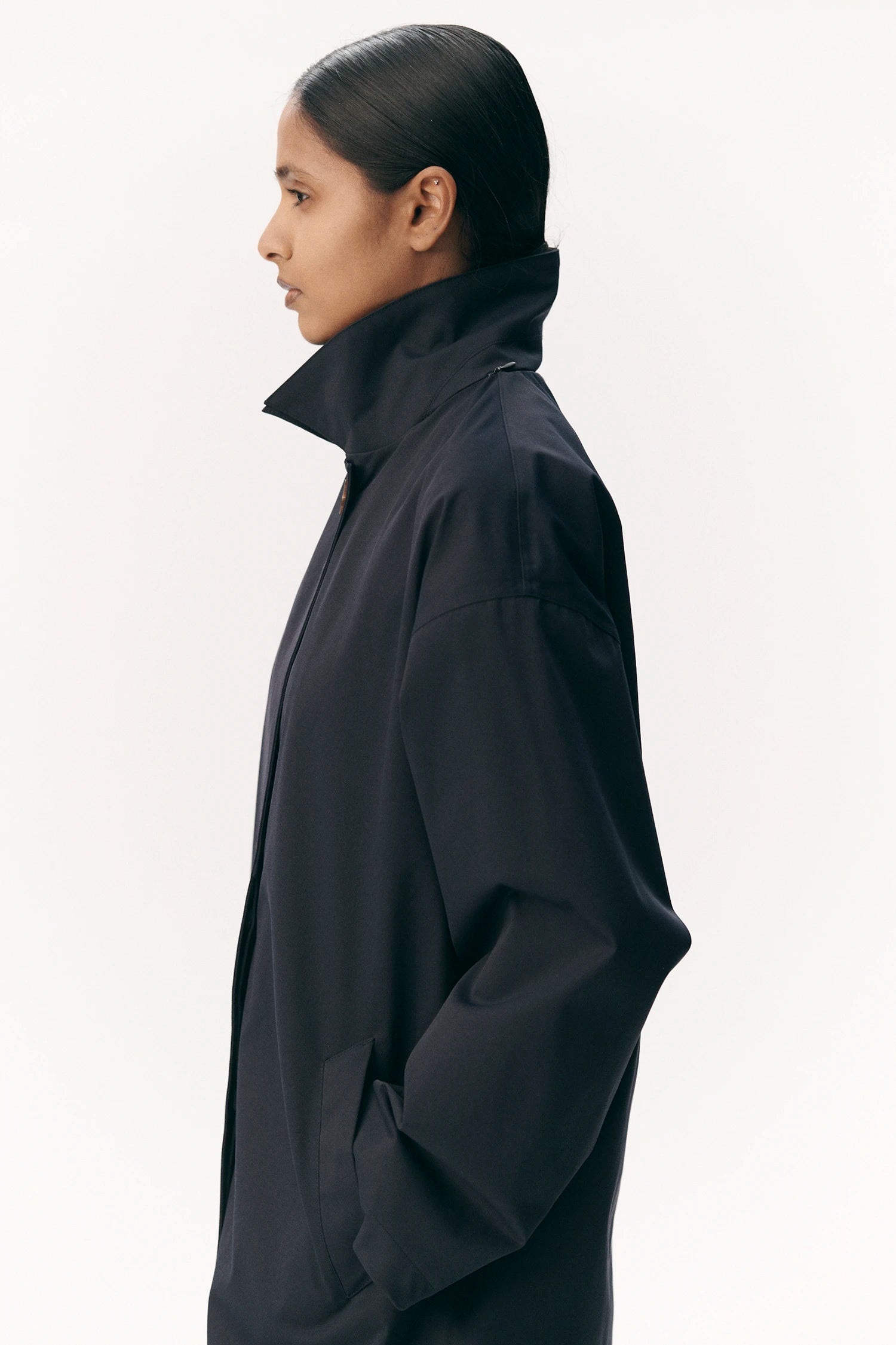 Model showcasing the Janice B Navy Coat in profile, featuring a high collar and sleek design.