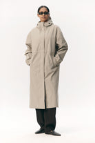 Model wearing a Roomy Long Tube Nylon Light Army Coat in beige, showcasing its waterproof design and adjustable features.