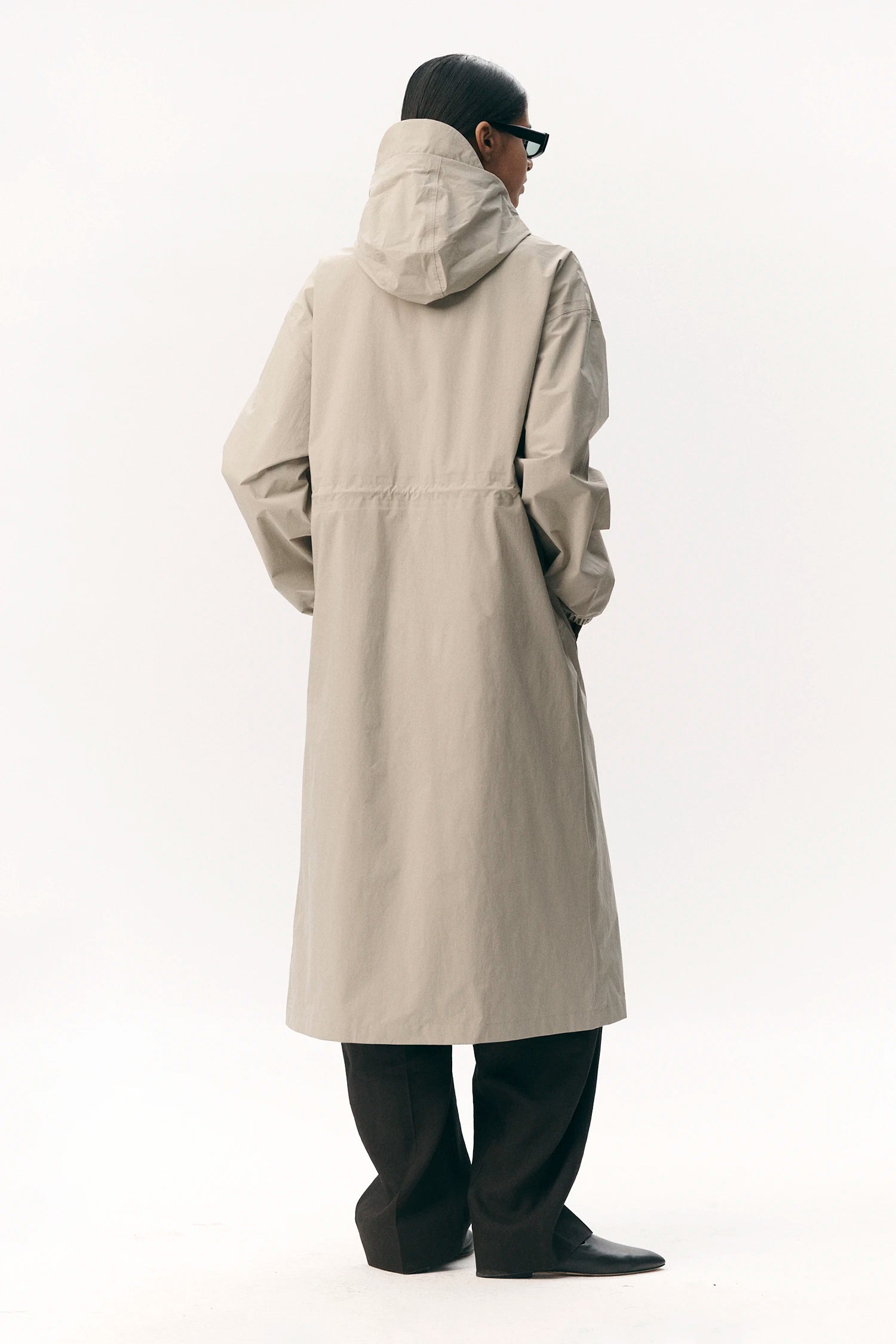 Back view of a person wearing the Roomy Long Tube Nylon Light Army Coat in beige color.