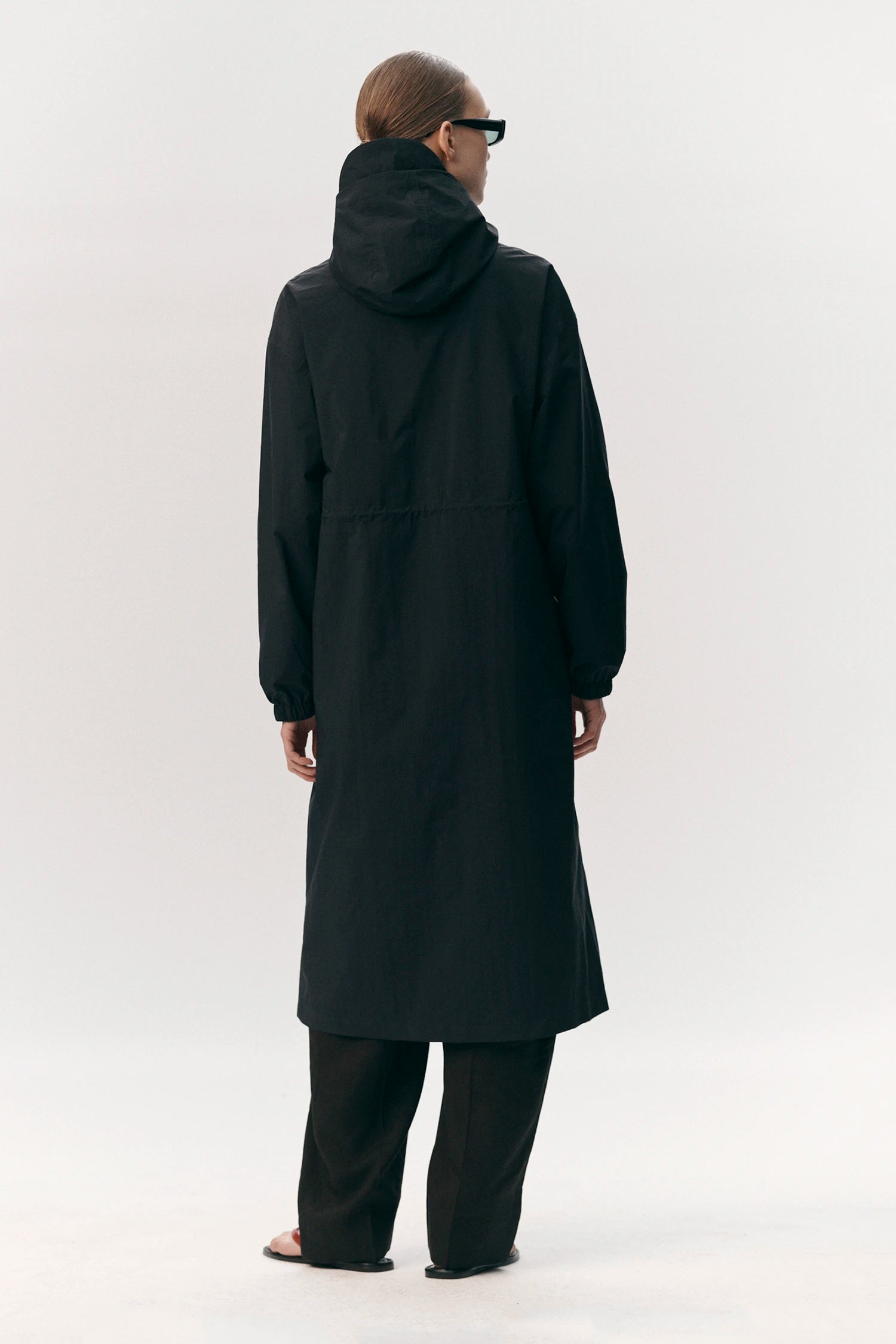 Model wearing a Roomy Long Tube Nylon Navy Coat from the back, showcasing its adjustable hood and long silhouette.