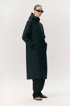 Roomy Long Tube Nylon Navy Coat worn by model, featuring a waterproof design and adjustable hood.
