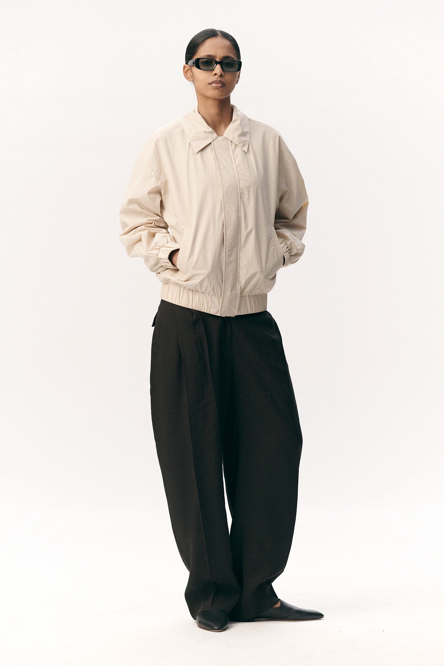 Model wearing Short Tracker WM Nylon Beige Jacket with relaxed fit and stylish sunglasses.