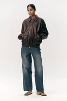 Short Tracker WM Dark Chocolate Jacket worn by a model with jeans, showcasing a stylish bomber design.
