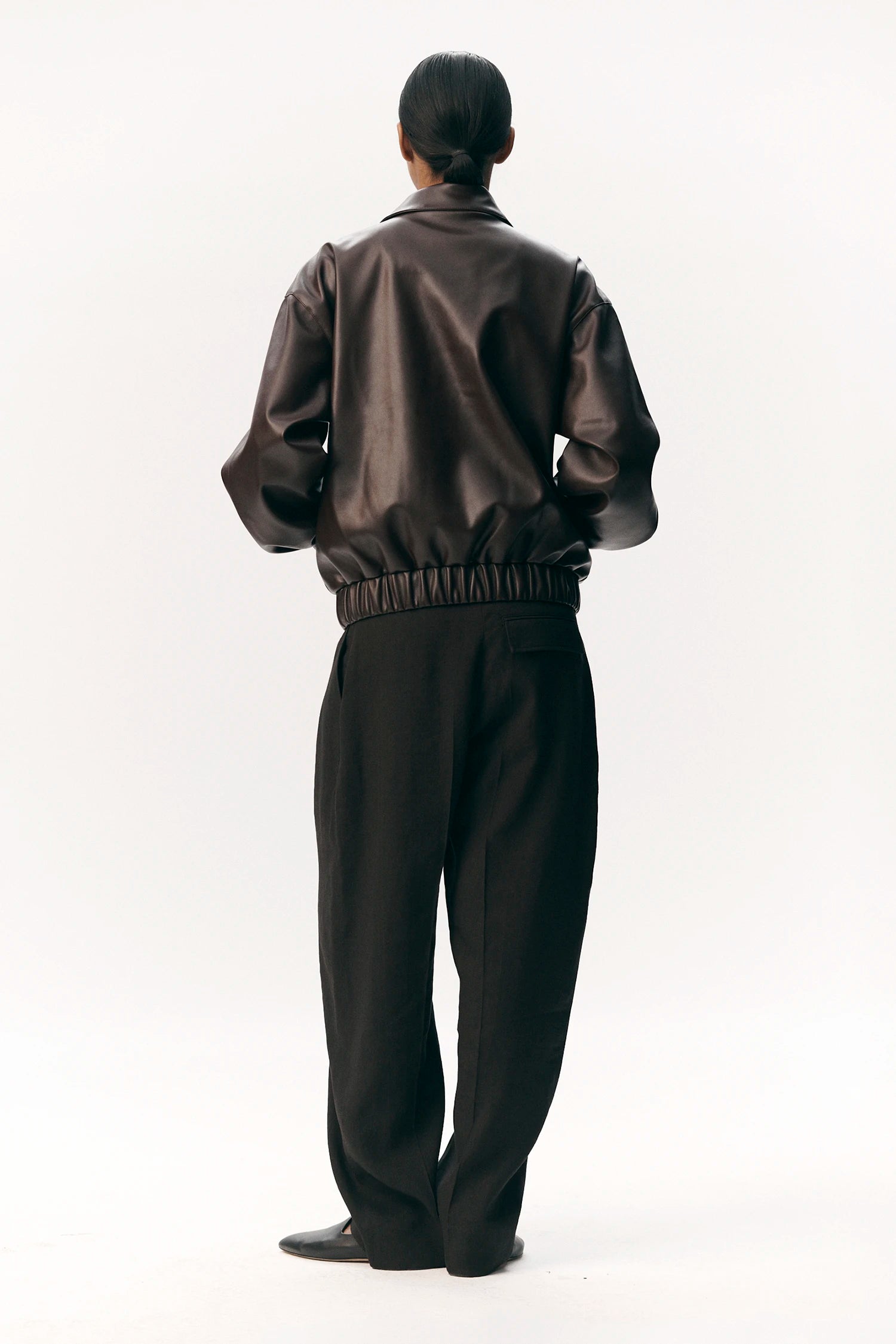Back view of a model wearing the Short Tracker WM Dark Chocolate Jacket with elastic waistband.