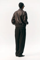Person wearing Short Tracker WM Dark Chocolate Jacket from the back, showcasing a stylish unisex bomber design.