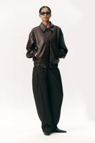 Model wearing Short Tracker WM Dark Chocolate Jacket paired with black wide-leg pants.