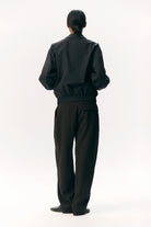 Model wearing a Short Tracker WM Nylon Navy Jacket, showcasing its unisex bomber fit and elastic waistband.