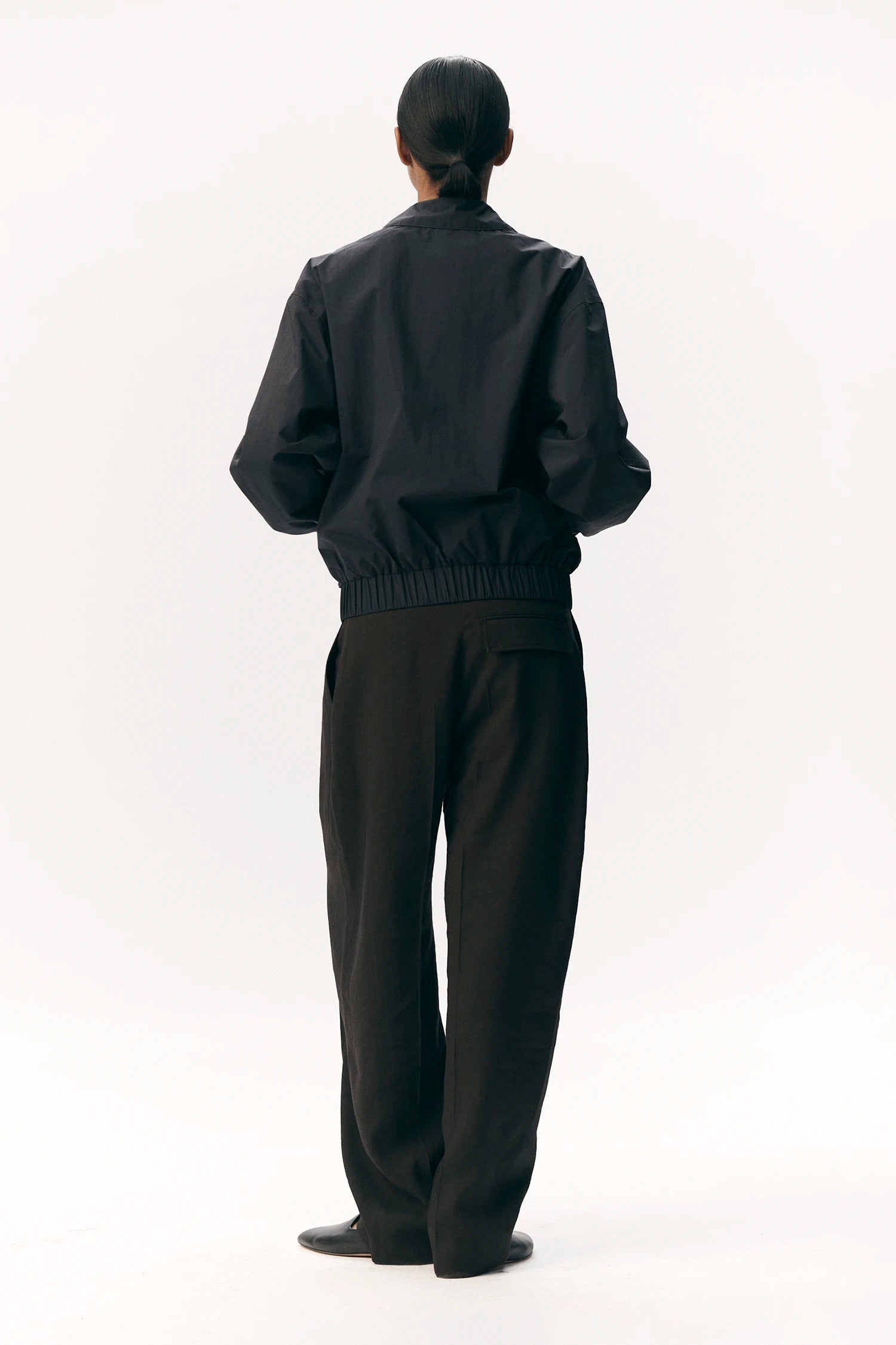 Model wearing a Short Tracker WM Nylon Navy Jacket, showcasing its unisex bomber fit and elastic waistband.