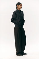 Short Tracker WM Nylon Navy Jacket displayed on a model wearing stylish black pants, showcasing its unisex bomber design.