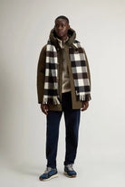 Model wearing an Arctic Parka Dark Green Coat with a checkered scarf and casual pants.