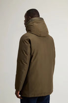 Back view of a man wearing the Arctic Parka Dark Green Coat with a protective hood.