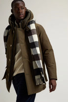 A model wearing the Arctic Parka Dark Green Coat paired with a checkered scarf, showcasing style and warmth.