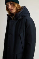 Stylish model wearing the Arctic Parka Melton Blue Coat, featuring a protective hood and patch pockets.
