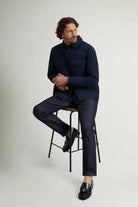 Man wearing Cloud Overshirt Melton Blue with stylish pants sitting on a stool.