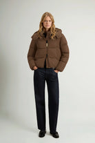 Model wearing Madison Jacket Dark Earth Coat by Woolrich, featuring a removable hood and windproof design.