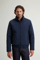 Model wearing Cloud Lewis Bomber Melton Blue Coat, a premium down filled bomber jacket in dark blue.