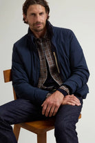 Cloud Lewis Bomber Melton Blue Coat displayed on a man sitting on a chair, showcasing premium design and fit.