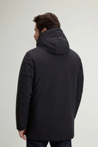 Man wearing a back view of a Stretch Parka Black Coat with a hood, showcasing its sleek design.