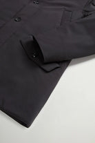 Stretch Parka Black Coat featuring a light stretch fabric, buttoned flap pockets, and a sleek design.