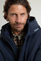 A man wearing the Stretch Parka Melton Blue Coat from Woolrich, showcasing the stylish design and premium features.