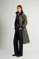 Model wearing a Waxed Coat Waxed Dark Green Coat with a contrasting collar and side pockets, styled for a chic look.