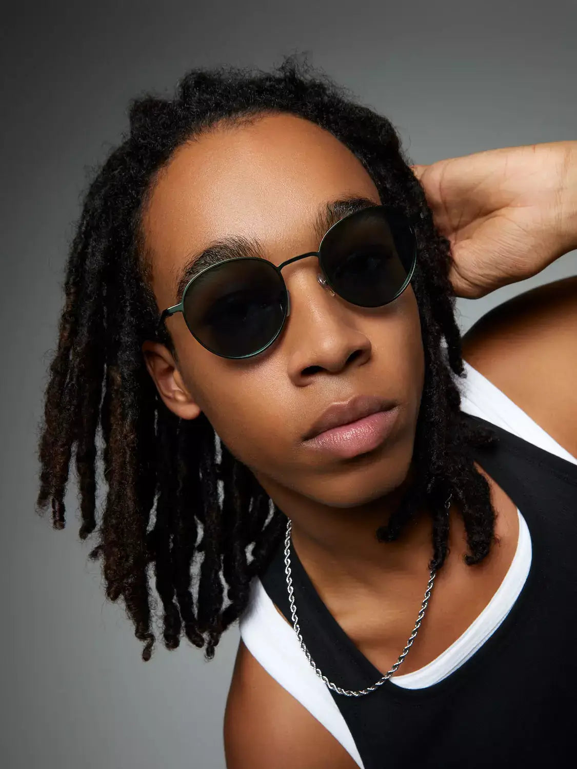 James Green Satin Cavee Sunglasses on a model with dreadlocks, showcasing dark green blue lenses and stainless steel frame.