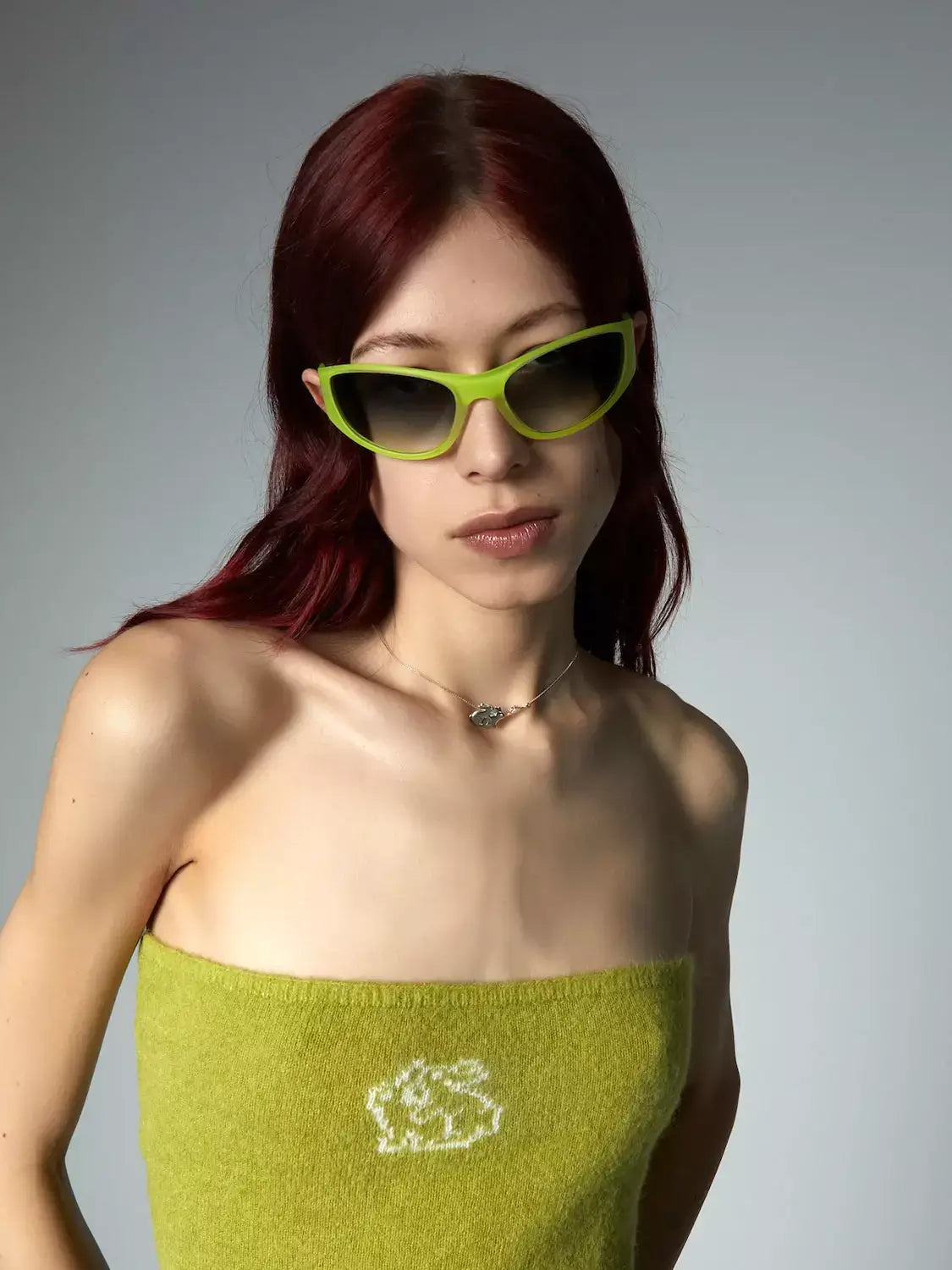 Neo Velvet Moon Sunglasses worn by a model with reddish hair, featuring a vibrant green outfit and stylish design.